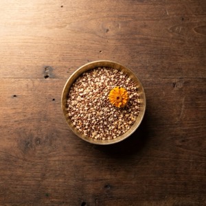 A brass bowl of raw ragi grain and urad dal